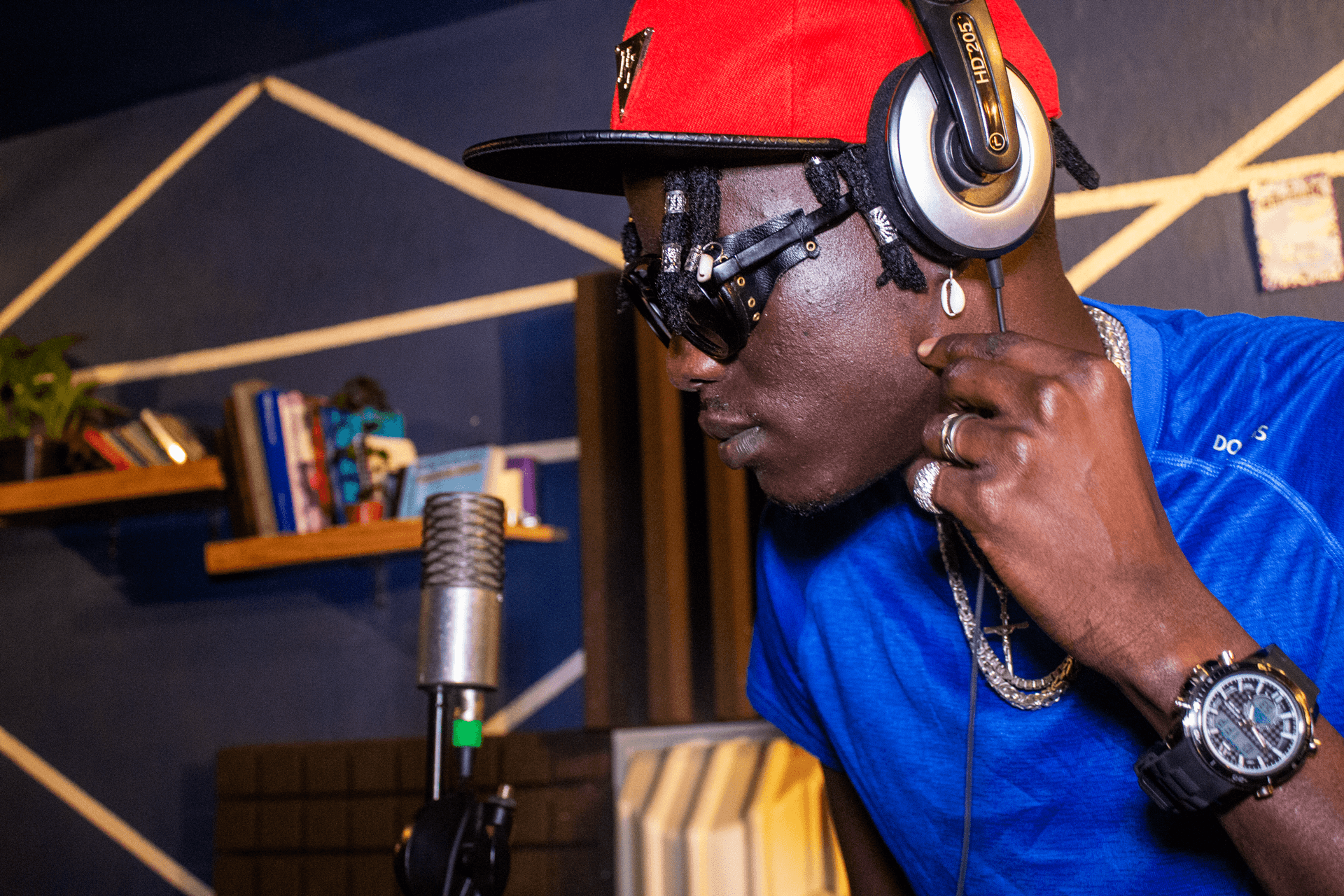 A vocalist in a red cap and headphones recording at a vintage ribbon microphone in the AISO studio